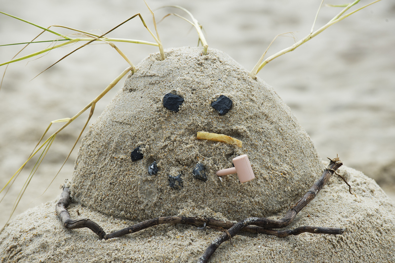 Anything found on the beach was allowed to be used to decorate the sculpture. Here sea grass, rocks, roots, a plastic toy and a french fry add humor to the crazy snowman. BY DENY HOWETH